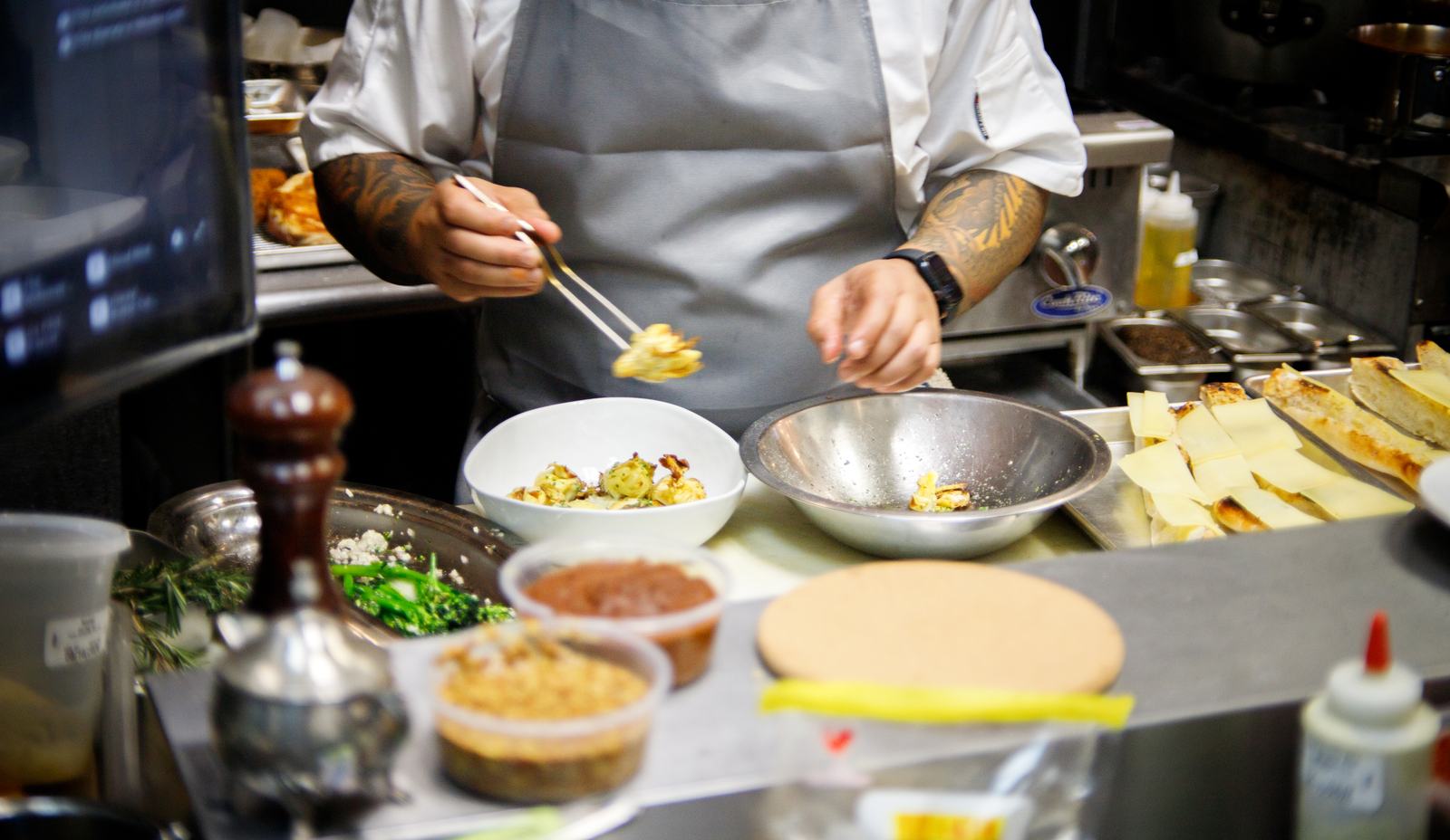 A chef plating a dish with tweezers on Solera's line