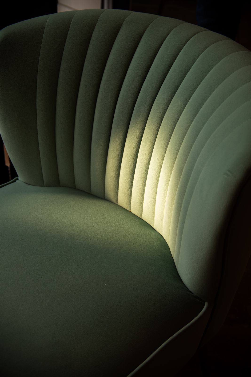 A sage velvet scalloped chair in warm light